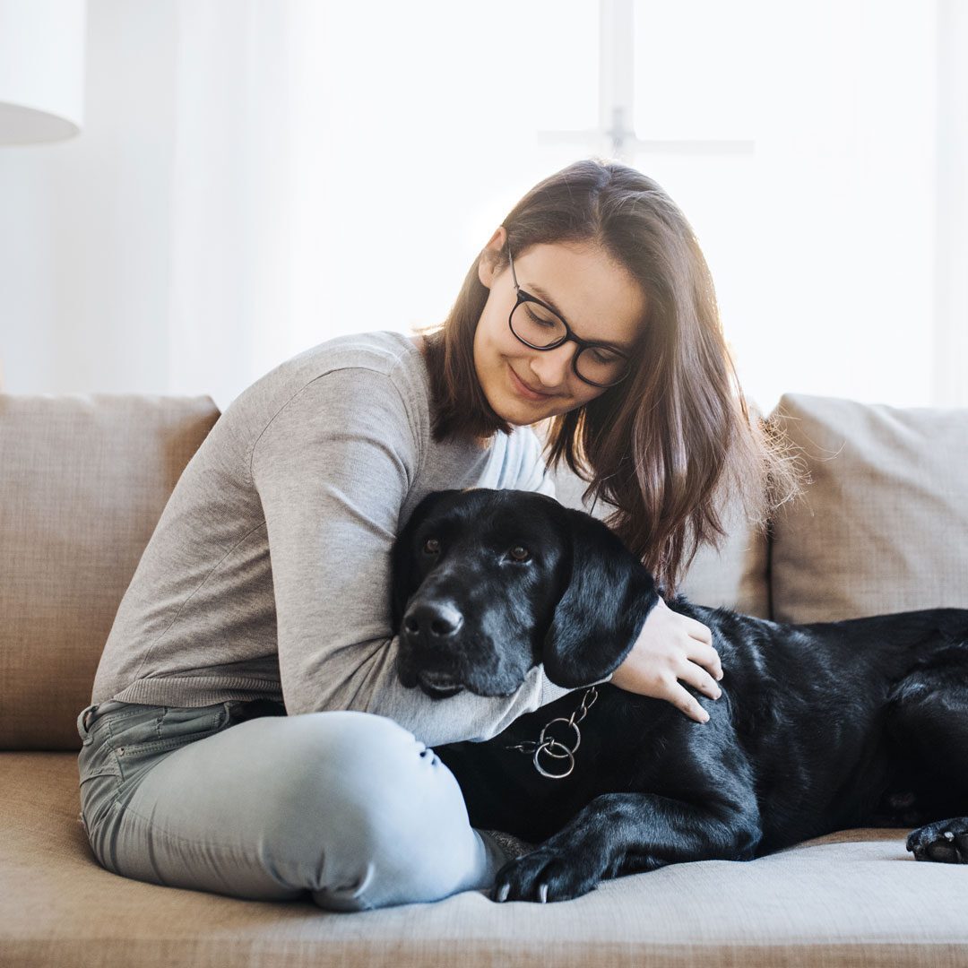 young woman cuddling on the couch with her dog